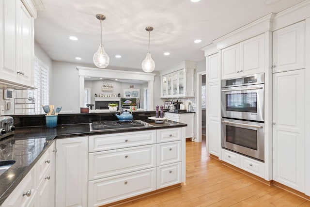 kitchen with glass insert cabinets, light wood finished floors, appliances with stainless steel finishes, and white cabinets