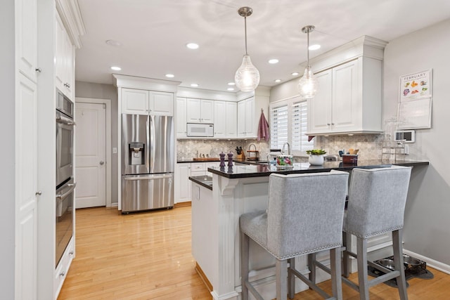 kitchen featuring a peninsula, white cabinets, stainless steel appliances, and a kitchen breakfast bar