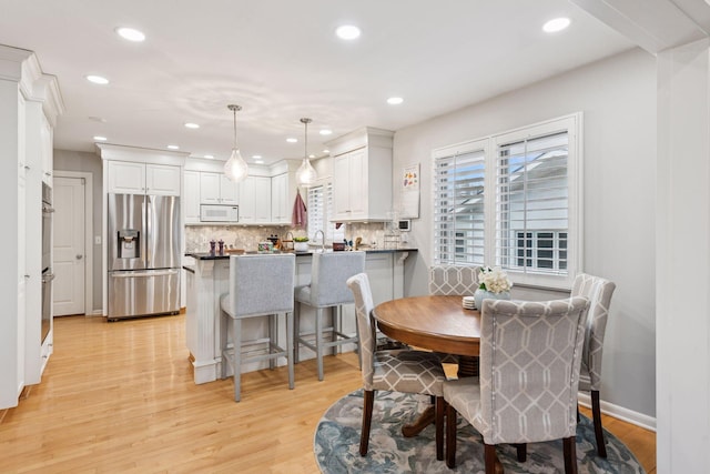 dining space featuring baseboards, light wood-style flooring, and recessed lighting