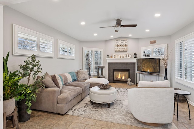 living room featuring baseboards, lofted ceiling, stone finish flooring, a fireplace, and recessed lighting