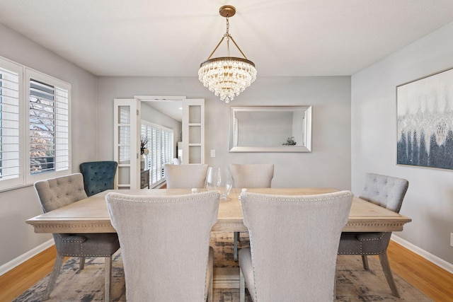 dining area with a notable chandelier, baseboards, and wood finished floors