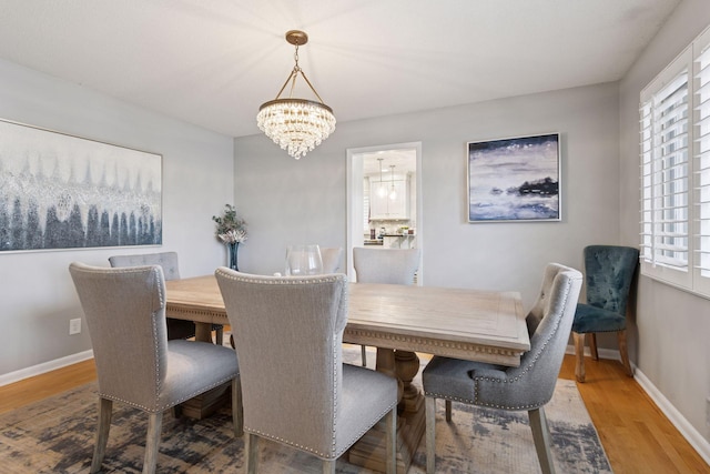 dining area with an inviting chandelier, baseboards, and wood finished floors