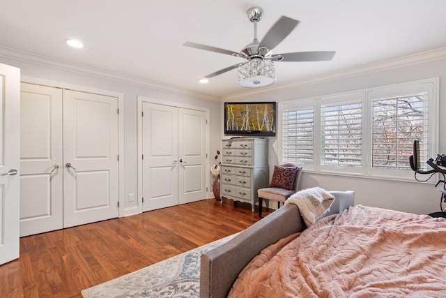 bedroom featuring multiple closets, crown molding, and wood finished floors