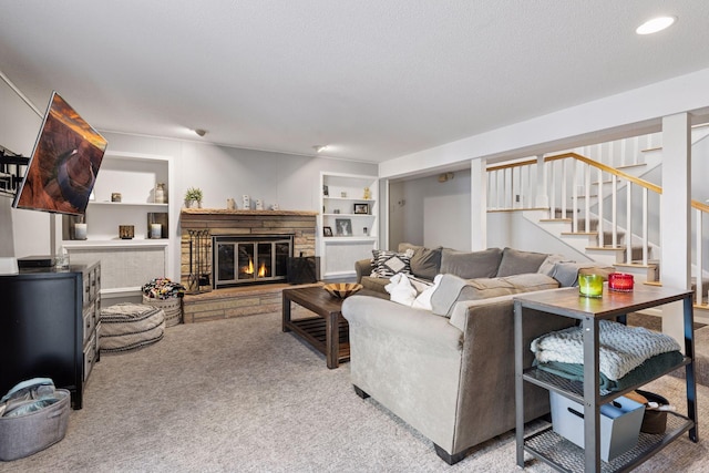 carpeted living area with stairs, a stone fireplace, a textured ceiling, and built in features