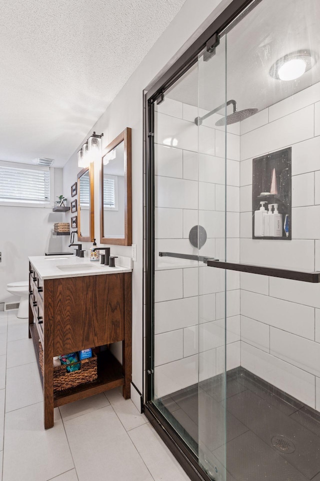 bathroom featuring toilet, vanity, a shower stall, a textured ceiling, and tile patterned floors