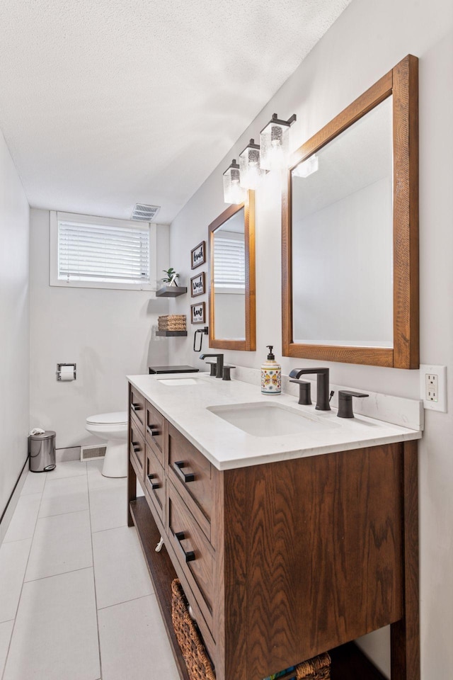 bathroom with double vanity, visible vents, toilet, a sink, and tile patterned floors