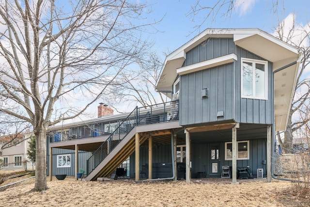 rear view of property with a chimney, stairway, board and batten siding, and a wooden deck