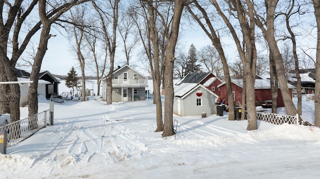 yard covered in snow featuring an outbuilding, a residential view, and fence