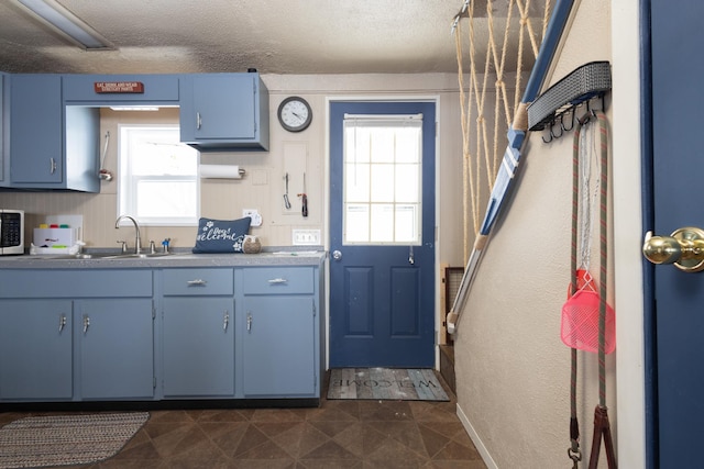 24932 Wall Lake Point Cir, Fergus Falls, MN 56537 - kitchen with blue cabinets, a textured ceiling, stainless steel microwave, and a sink