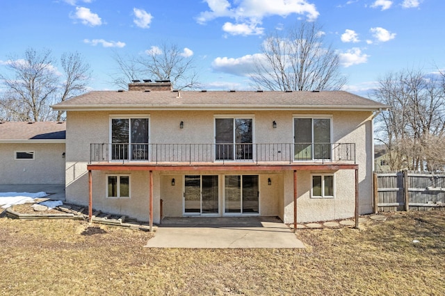 rear view of property featuring a patio, fence, a chimney, and stucco siding