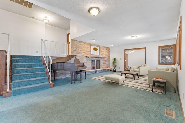 carpeted living area featuring visible vents, a textured ceiling, stairway, a fireplace, and ceiling fan