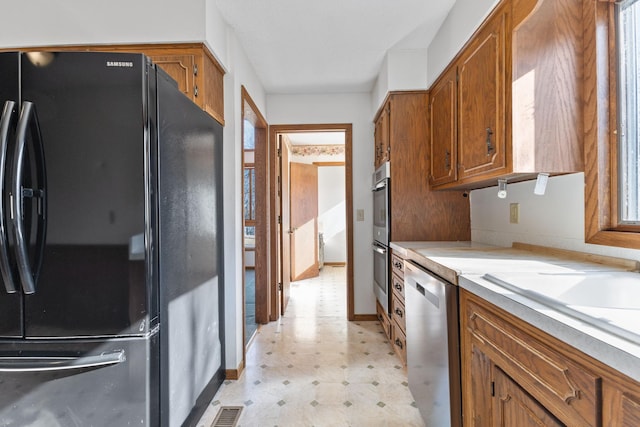 kitchen with visible vents, light floors, light countertops, appliances with stainless steel finishes, and brown cabinetry