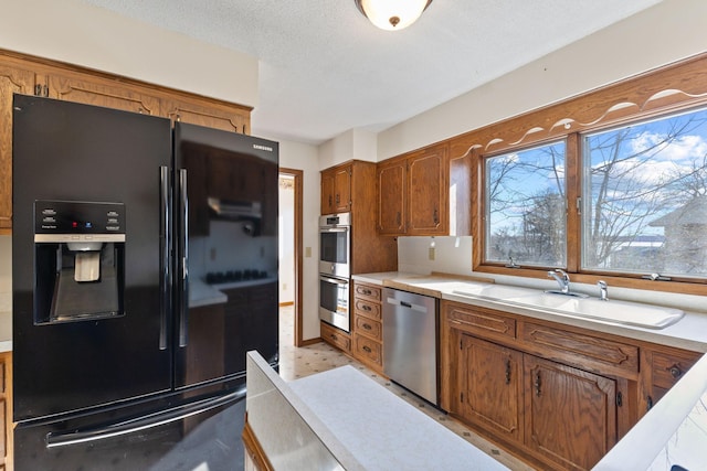 kitchen with a sink, light countertops, brown cabinets, and stainless steel appliances