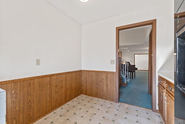 interior space featuring wooden walls, wainscoting, stairway, and light floors