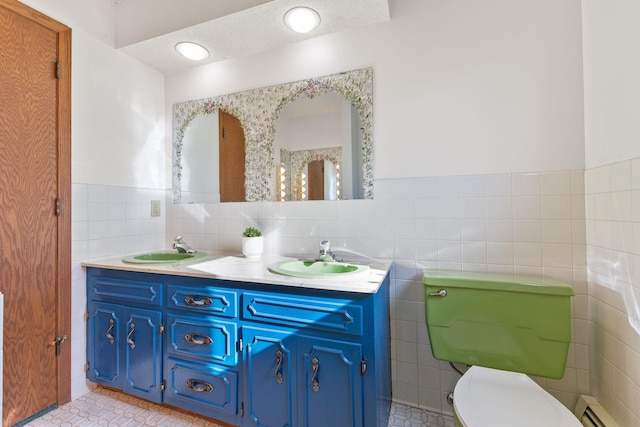 full bathroom featuring a sink, tile walls, double vanity, and tile patterned floors