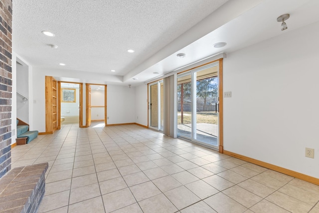 spare room featuring light tile patterned floors, baseboards, and a textured ceiling