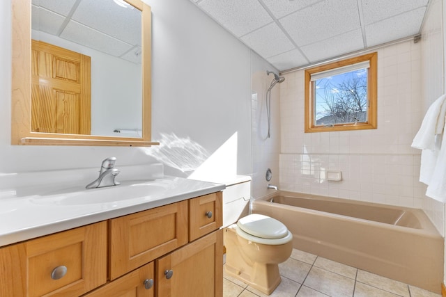 bathroom featuring toilet, a drop ceiling, vanity, tile patterned flooring, and shower / bathtub combination