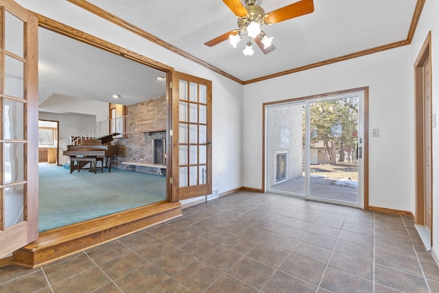 doorway to outside with dark tile patterned flooring, ornamental molding, a textured ceiling, a fireplace, and baseboards