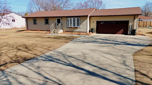 single story home with concrete driveway, a garage, and a shingled roof