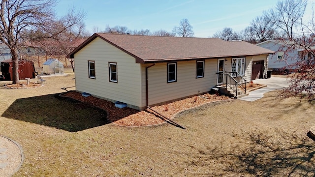 view of front of house featuring an outbuilding, driveway, a shingled roof, and an attached garage