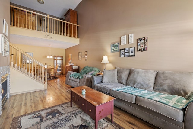 living room with an inviting chandelier, stairs, a high ceiling, and wood finished floors