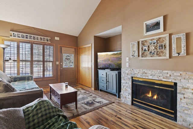 living area with a fireplace, high vaulted ceiling, and wood finished floors