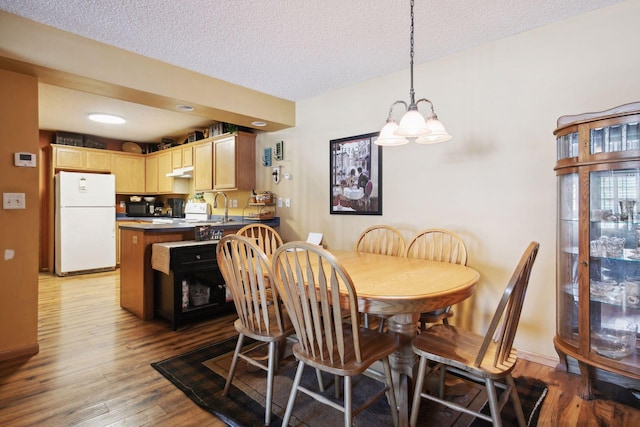 dining room featuring a textured ceiling, baseboards, and wood finished floors