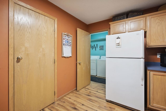 kitchen featuring light brown cabinets, washing machine and dryer, freestanding refrigerator, and light wood-style floors