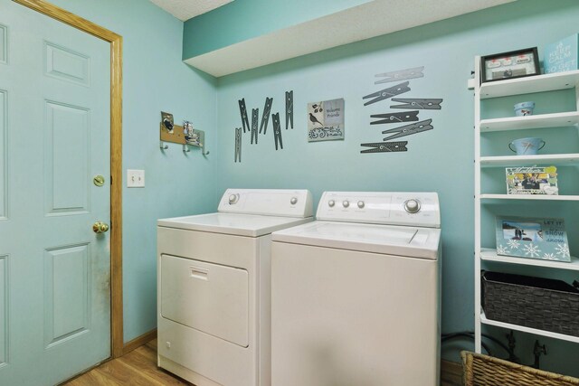 clothes washing area with laundry area, light wood-style flooring, and washer and clothes dryer