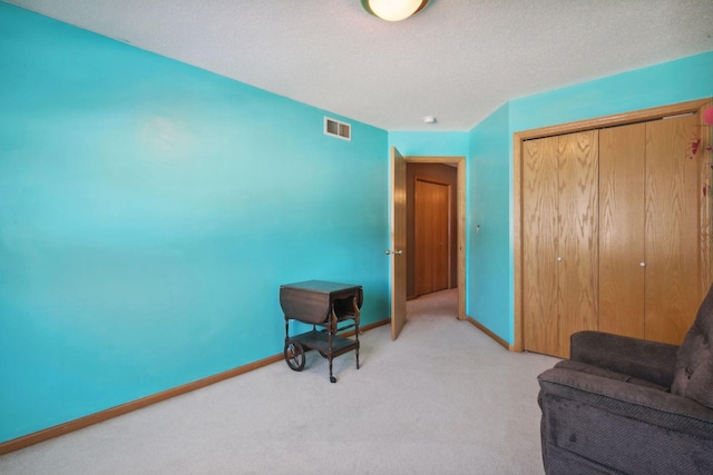 sitting room featuring light carpet, visible vents, baseboards, and a textured ceiling