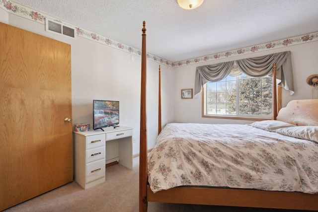 bedroom featuring visible vents, a textured ceiling, and light colored carpet