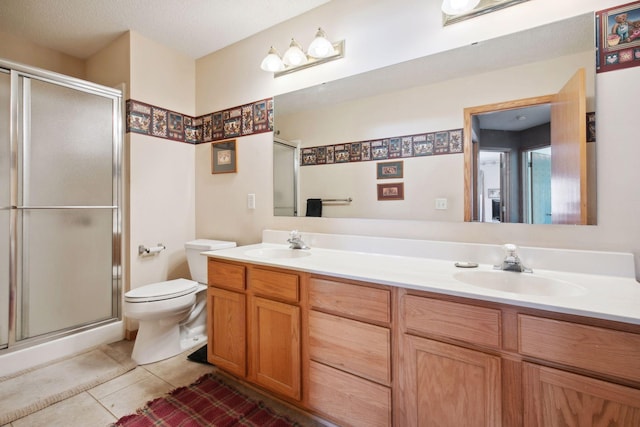 bathroom featuring double vanity, a shower stall, a sink, and tile patterned floors