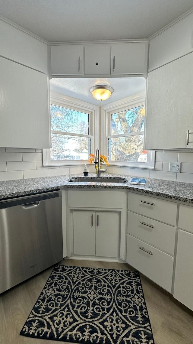 kitchen with a sink, light stone countertops, white cabinets, and dishwasher