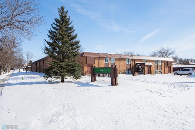 snow covered rear of property featuring brick siding