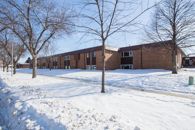 snow covered rear of property featuring brick siding