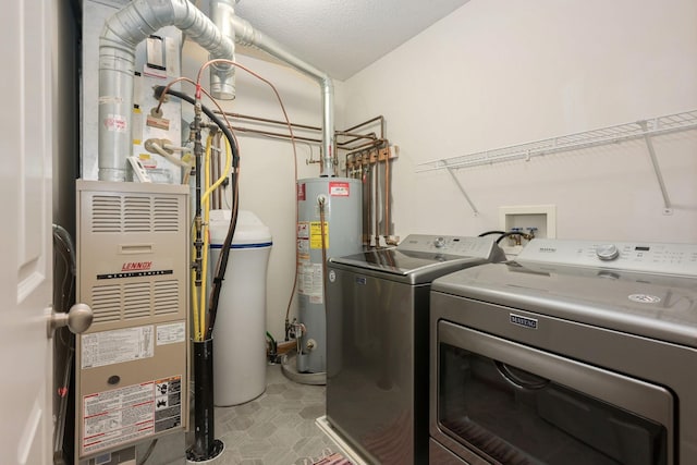 laundry room with washing machine and dryer, laundry area, water heater, and a textured ceiling