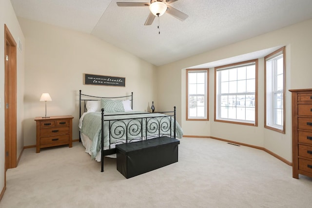 bedroom with baseboards, visible vents, light colored carpet, vaulted ceiling, and a textured ceiling