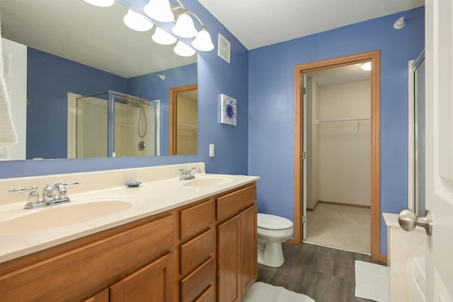 bathroom with double vanity, a stall shower, a sink, and a walk in closet