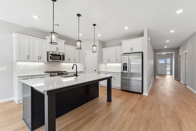 kitchen with stainless steel appliances, light wood-style flooring, a sink, and tasteful backsplash