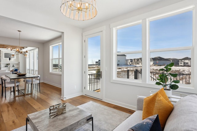 living room with a notable chandelier, light wood-style flooring, and baseboards