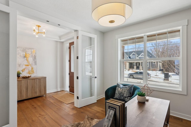 sitting room with an inviting chandelier, visible vents, baseboards, and wood finished floors