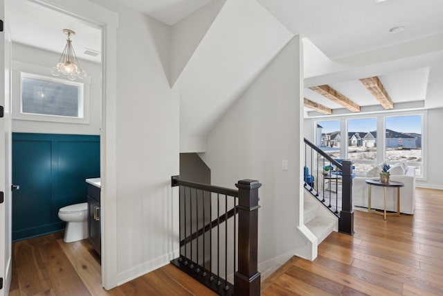 interior space featuring a notable chandelier, beam ceiling, baseboards, and wood finished floors