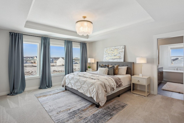 bedroom featuring baseboards, a tray ceiling, and light colored carpet