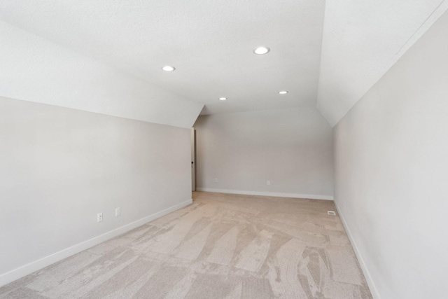 additional living space featuring lofted ceiling, light colored carpet, baseboards, and recessed lighting