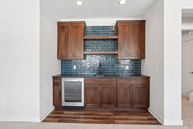 bar with beverage cooler, visible vents, a sink, and backsplash