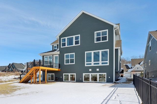 snow covered back of property featuring fence, stairway, and a wooden deck