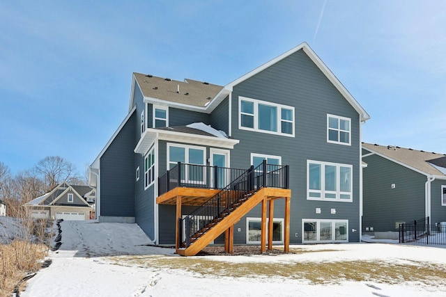 snow covered house with stairway and a wooden deck