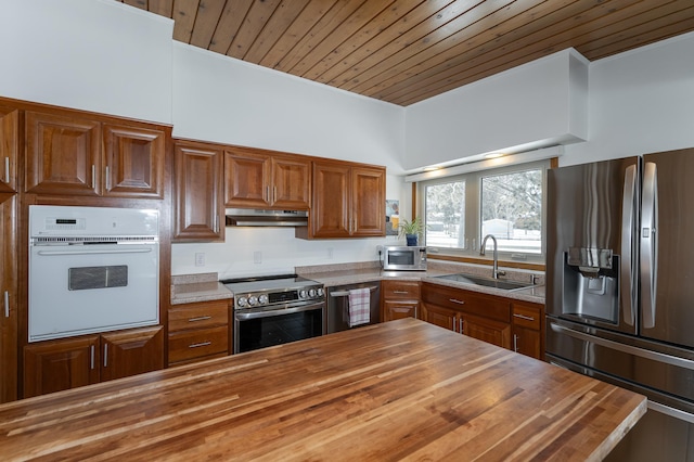 kitchen featuring wood ceiling, wood counters, appliances with stainless steel finishes, under cabinet range hood, and a sink