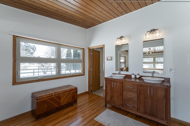 full bath with double vanity, wooden ceiling, a sink, and wood finished floors