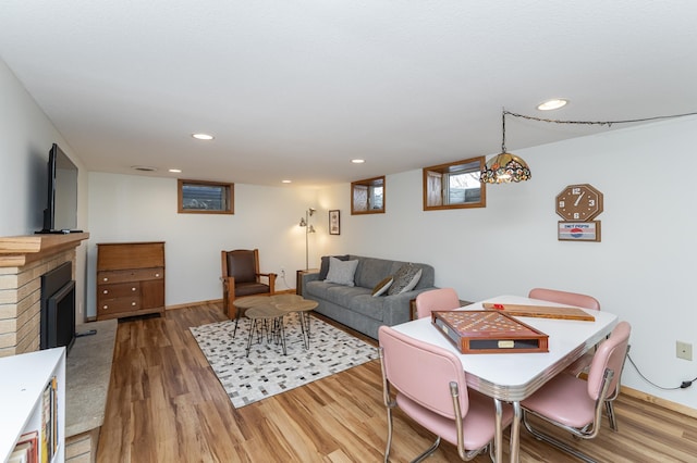 living room with a brick fireplace, wood finished floors, and recessed lighting